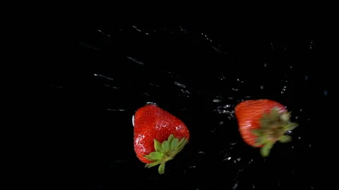 Ripe red strawberries fall in slow motion on a wet black Stock Footage 134239533