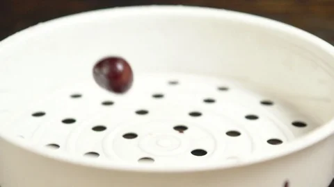 Ripe red sweet cherries bouncing into a colander Stock Footage 94052535