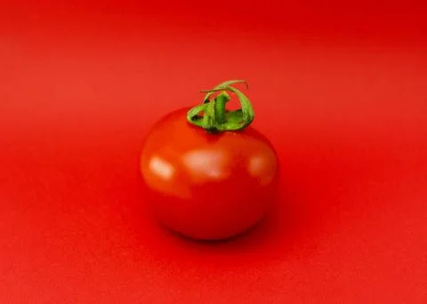 Ripe, red tomato isolated on a solid red background 写真素材