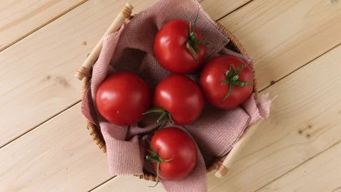 Ripe red tomatoes rotating in a basket on a wooden table Stock Footage 337886091