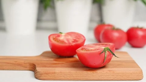 Ripe red tomatoes with splashes from water lie on wooden board on kitchen table Видео 205515460