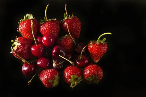 Ripe strawberries and cherries on a solid background, healthy vegetarian food Foto stock