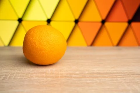 Ripe sweet orange lies on a wrinkled wooden table on a colored background Stock Photos