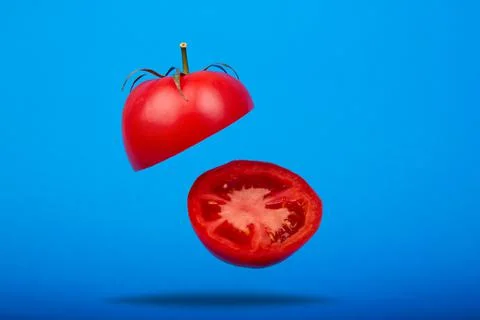 A ripe tomato cut in the air on a blue background Stock Photos