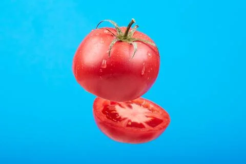 A ripe tomato cut in the air on a blue background Stock Photos