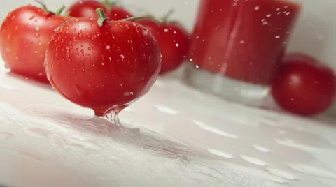 Ripe tomato falls on a table, splashing drops Видео 62681821