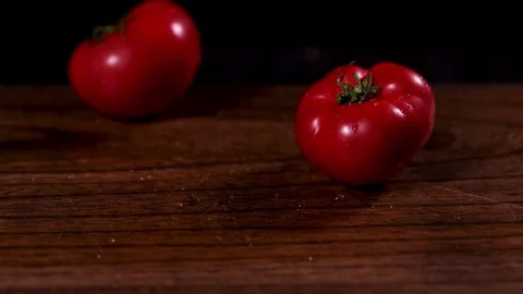 Ripe tomatoes are being carefully arranged on a wooden tabletop in a dimly lit Stock Footage 277423631