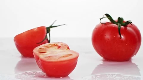 A ripe tomatoes are falling on the white table, splashing water drops. Stock Footage 147380026