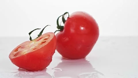 A ripe tomatoes are falling on the white table, splashing water drops. Stock Footage 147380027