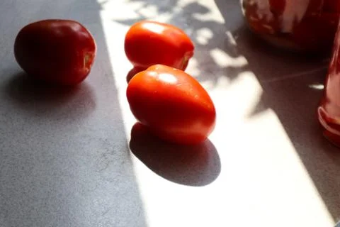 Ripe tomatoes on the kitchen table, shadows from objects Stock Photos