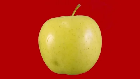 Ripe yellow apple on a red background rotates. Stock Footage 162405939