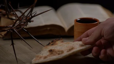Ripped Bread being placed on table with cup of Wine, Crown of Thorns and Bible Video stock 128585612