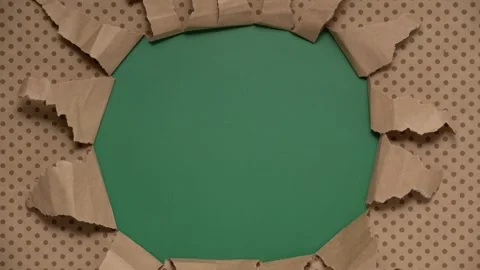 Ripped brown polka dot wrapping paper revealing a green background. Stop motion Stock Footage 334003898