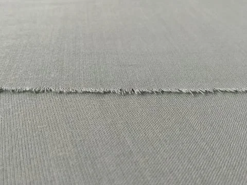 Ripped edge of fine woolen fabric in green or blue. Loose threads at the edge Stockfoto's