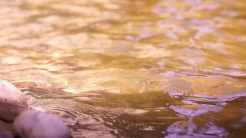 Ripples and reflections from the sun's glare on wavy water surface in golden Видео 252229840