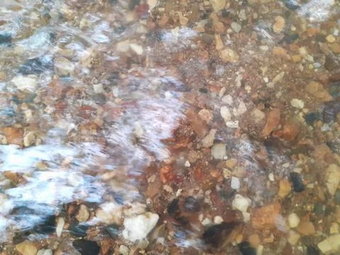 Ripples in the river flow through many stones, colorful summer to bright sun. Stock Photos