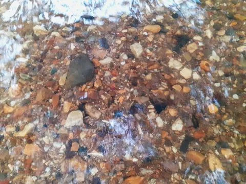 Ripples in the river flow through many stones, colorful summer to bright sun. Stock Photos