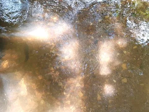 Ripples in the river flow through many stones, colorful summer to bright sun. Stock Photos