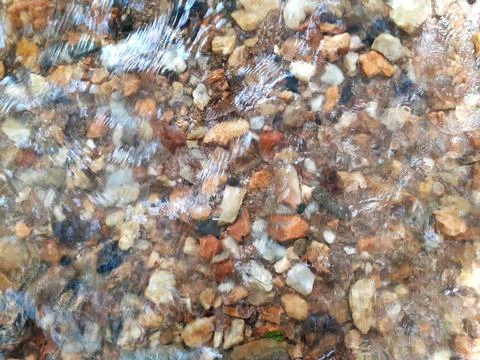 Ripples in the river flow through many stones, colorful summer to bright sun. Stock Photos