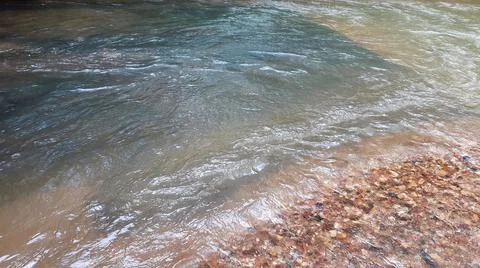 Ripples in the river flow through many stones, colorful summer to bright sun. Stock Photos