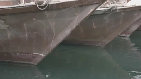 The ripples of the waves reflect the sun on the hulls of three fishing boats Stock Footage 135453323