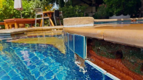 Rippling Clear Water Passes Damaged Blue Pool Tiles in a Leafy Backyard, Showing Stock Footage 345141078
