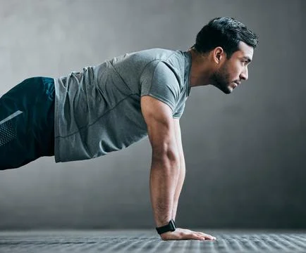 Rise and grind. a handsome young male athlete doing pushups against a grey Stock Photos