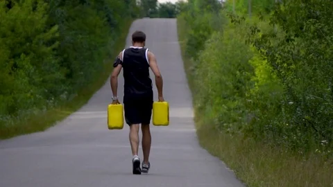 Rise of the road man runs forward with two yellow jerrycans Video stock 80436449