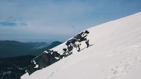 Rising up aerial shot two active hiker traveler snowboarding and skiing climbing Stock Footage 120833757