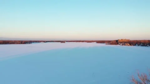 Rising from behind leafless trees in winter at sunset revealing the snow Stock Footage 163981763