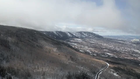 Rising drone shot into clouds high above a snowy winding mountain road Stock Footage 123883062