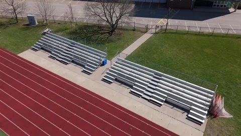 RIsing drone shot of empty bleachers with running track in foreground Stock Footage 333525401
