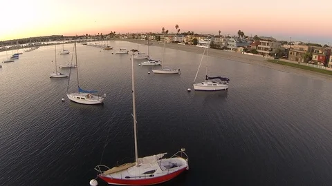 Rising drone shot over sailing boats parked on a bay near sandy shoreline. Stock Footage 129062076