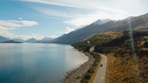 Rising drone shot of van driving beside blue lake in New Zealand Stock Footage 90270331