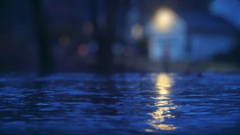 Rising flood waters encroach on the front steps of a nearby home at night Stock-Footage 100773320