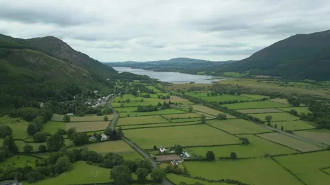 Rising high above green patchwork fields with mountains and lake on Video stock 247975485
