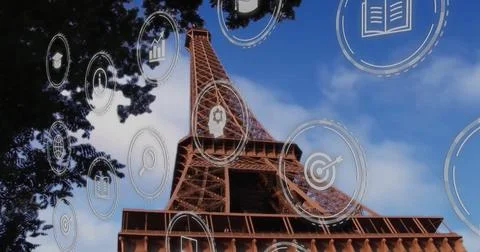 Rising iconic Eiffel Tower displaying digital overlay icons beside dark tree Stock Photos