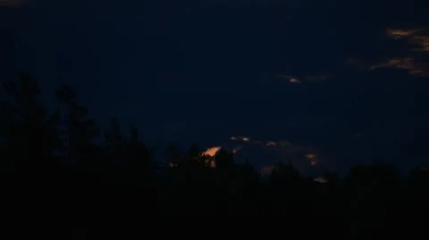 Rising of moon above the forest through clouds. Night is a summer. Stockbeeldmateriaal 44229412