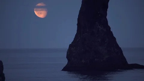 Rising moon low over calm ocean Renisdrangar sea stack Iceland Stock Footage 111571386
