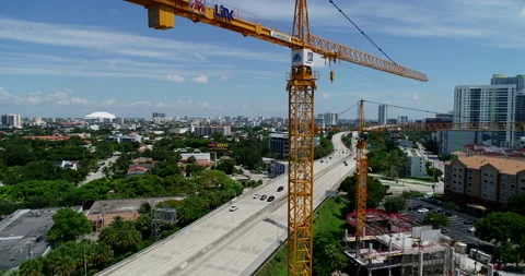 Rising over construction cranes along the highway in Miami Stock Footage 157277268