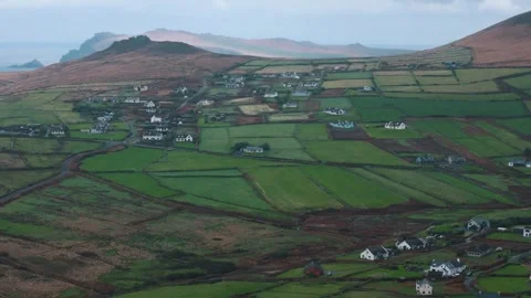 Rising over Irish fields as sunlight spills through clouds onto distant cliffs Stock Footage 328471393