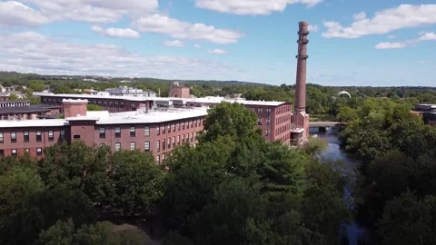 Rising over trees towards an old mill and smoke stack next to the Charles Stock Footage 139585567