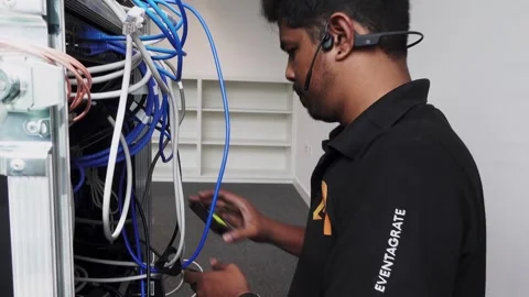 Rising shot of a hardware engineer plugging in cables into the back of a Stock Footage 244787966