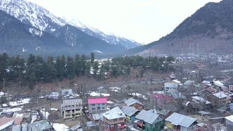 Rising shot of mountains , deodar trees covered with snow and colourful houses Stock Footage 202603462
