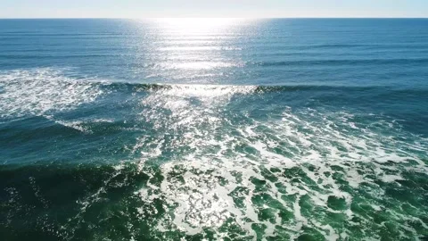 Rising shot on waves in the ocean and sun reflecting off the water Stock Footage 155464614