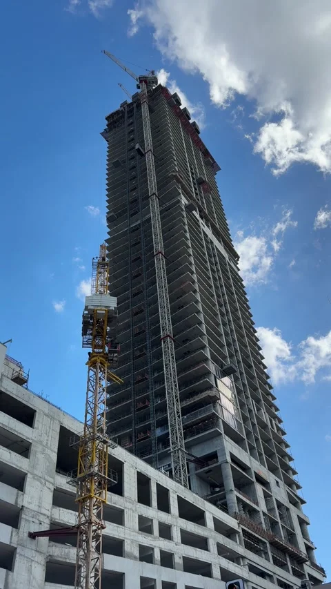 Rising skyscraper under construction, viewed from below against a bright blue Stock Footage 301860165