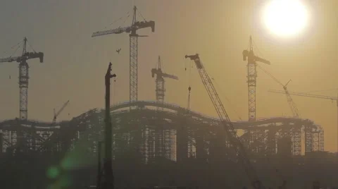 The rising sun appears from behind a silhouette building of the construction Stock-Footage 67273944