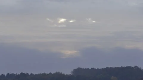 Rising sun shining through heavy clouds above forest time lapse Stock Footage 220806088