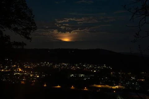 Rising super moon with clouds over cityscape. Stock Photos