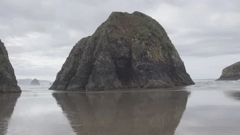 Rising tide in front of towering sea stack on a cloudy day, Canon Beach Video stock 332255406